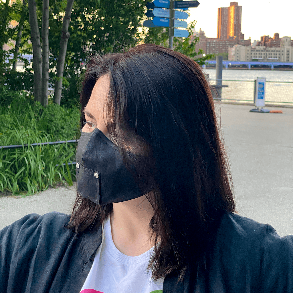 A stylish black face mask made from 100% organic linen, featuring a straw hole for easy sipping, adjustable elastic loops, and a moldable nose bridge.