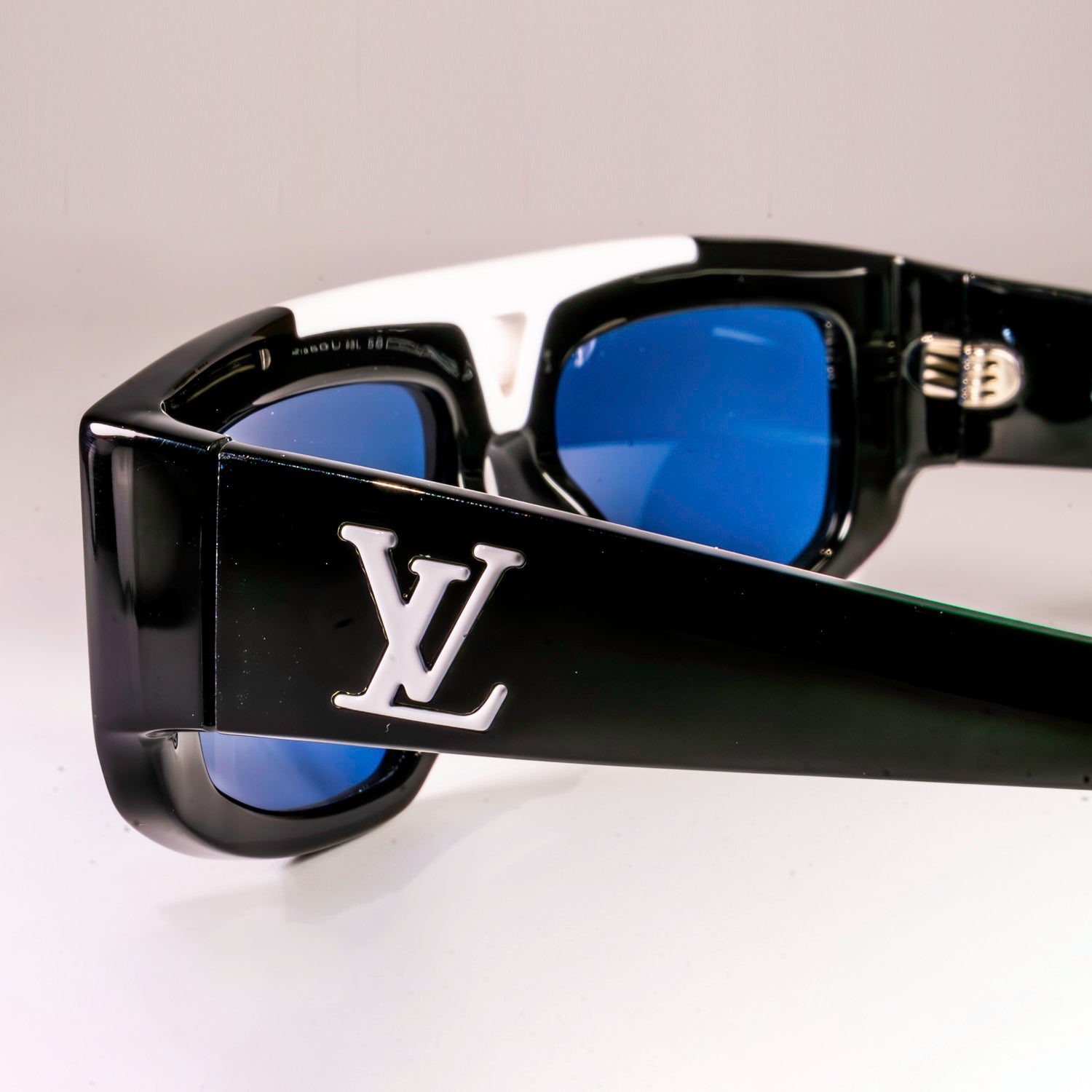 Stylish LV 1.1 Evidence Sport Sunglasses with black acetate frames and grey lenses, featuring white V-shape bridge and engraved Monogram motifs.