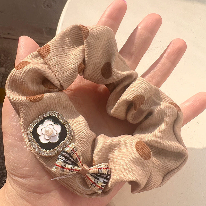 Milky white leather hair tie featuring hearts and bows, elegantly held by a woman's hand.