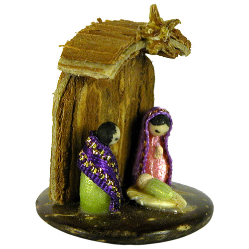 Miniature nativity scene featuring Mary, Joseph, and Baby made from seeds and ribbon, set on a coconut base with Cat's Claw Bark.