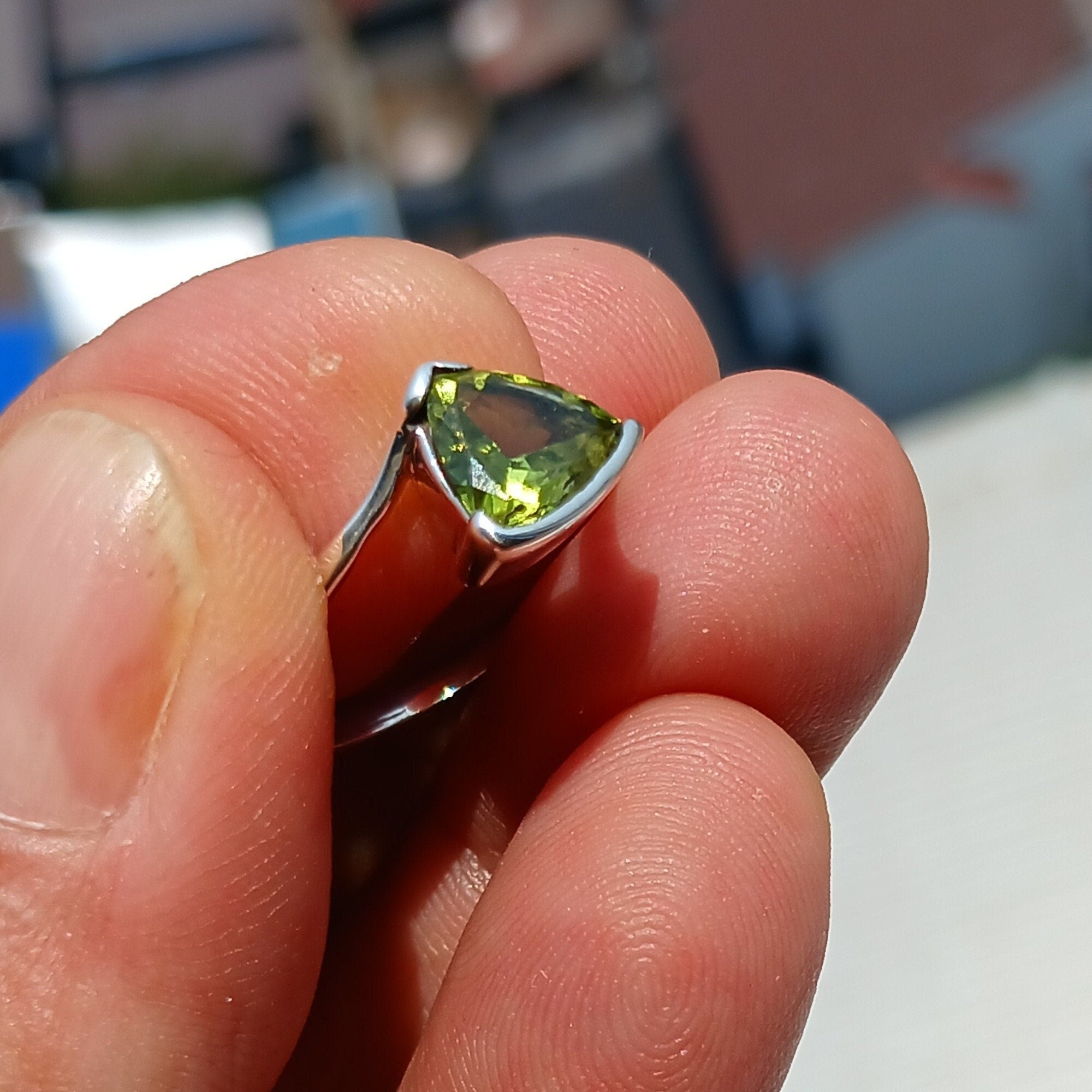 A stunning Minimalist Peridot Silver Ring featuring a unique triangle-shaped green Peridot stone set in a polished sterling silver band.