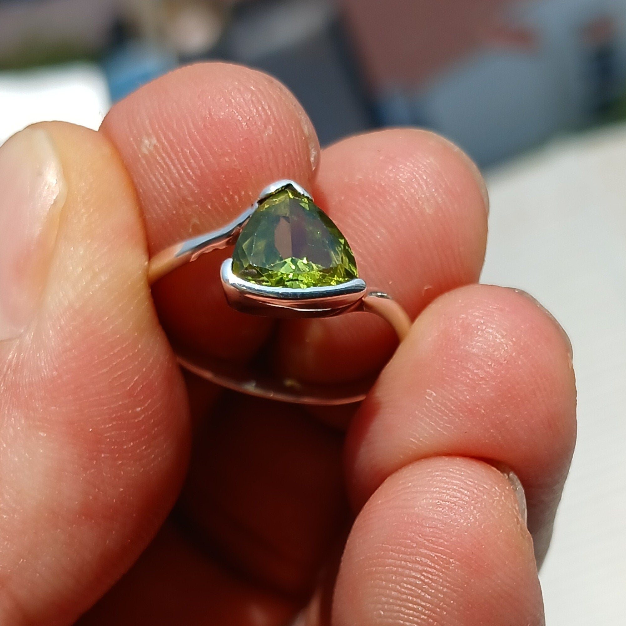 A stunning Minimalist Peridot Silver Ring featuring a unique triangle-shaped green Peridot stone set in a polished sterling silver band.