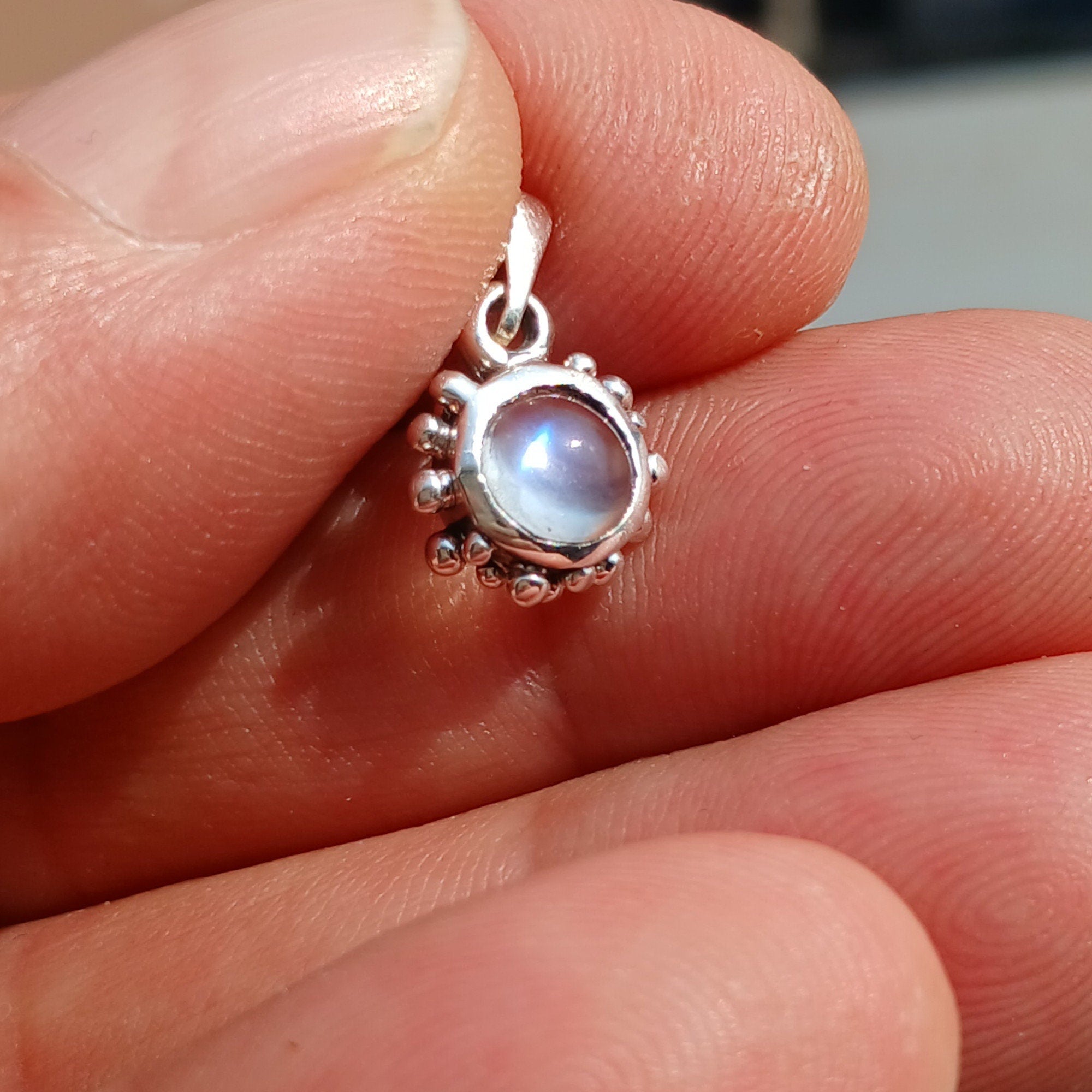 A beautiful round Ceylon moonstone pendant set in 925 sterling silver, showcasing its polished surface and elegant design.