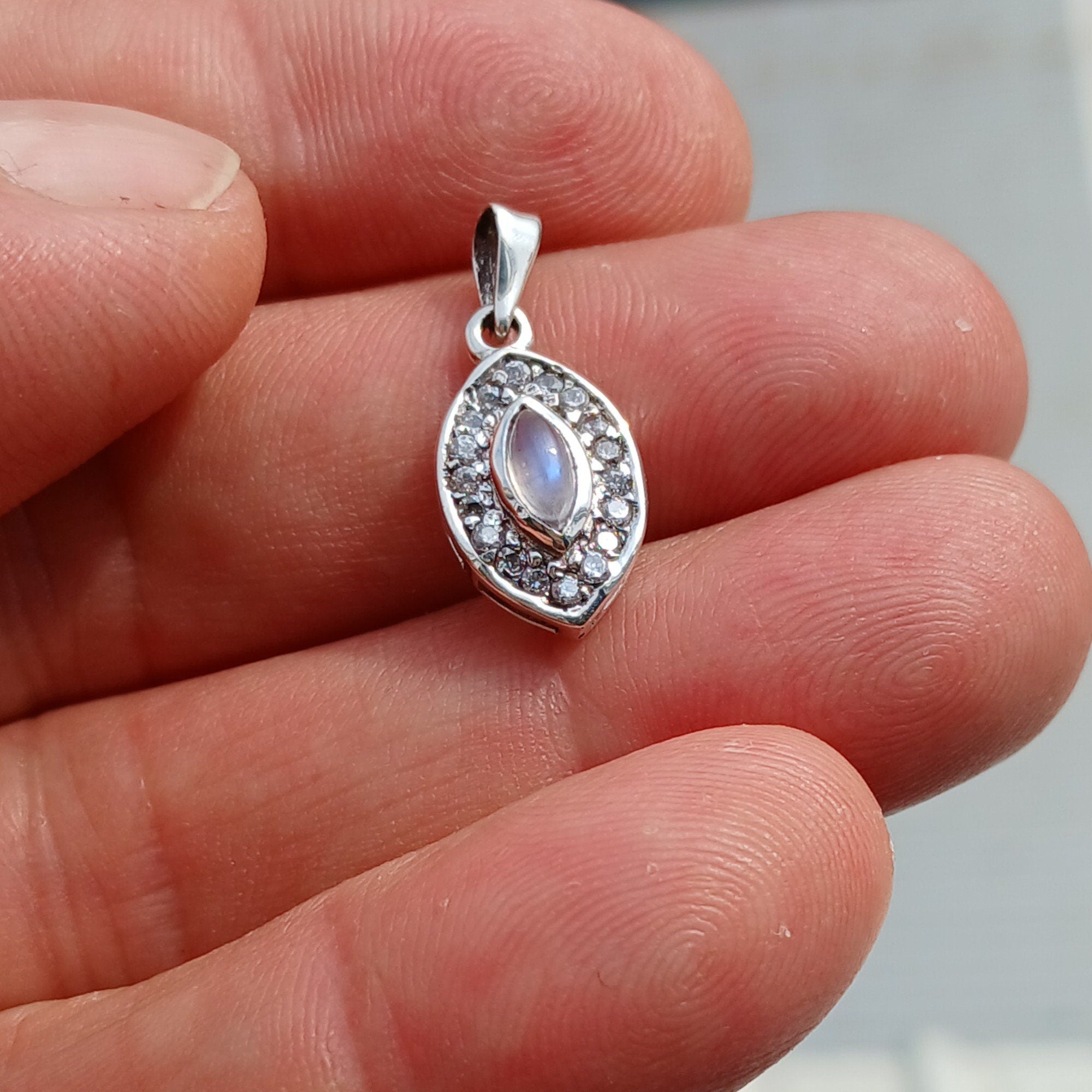 A stunning Moonstone Pendant in sterling silver, featuring a central moonstone surrounded by seven sparkling cubic zirconias.