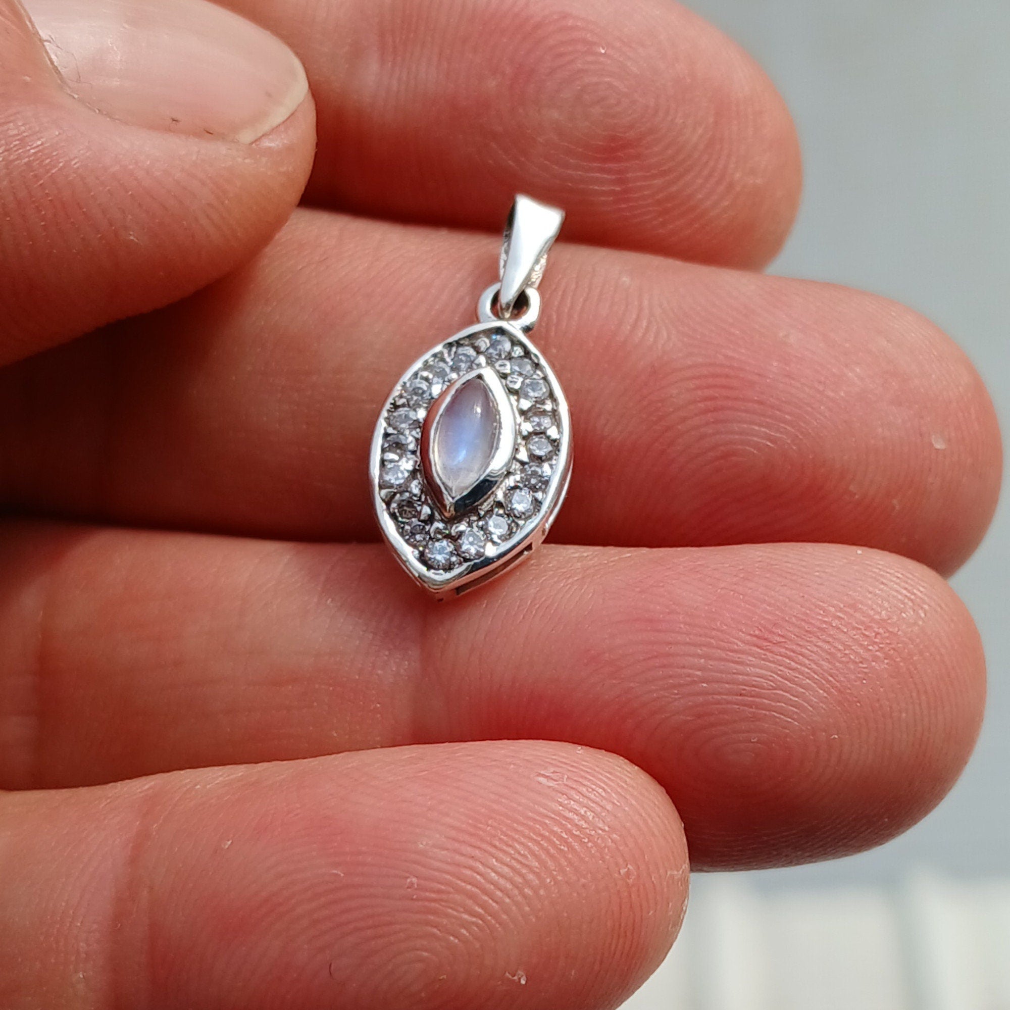 A stunning Moonstone Pendant in sterling silver, featuring a central moonstone surrounded by seven sparkling cubic zirconias.