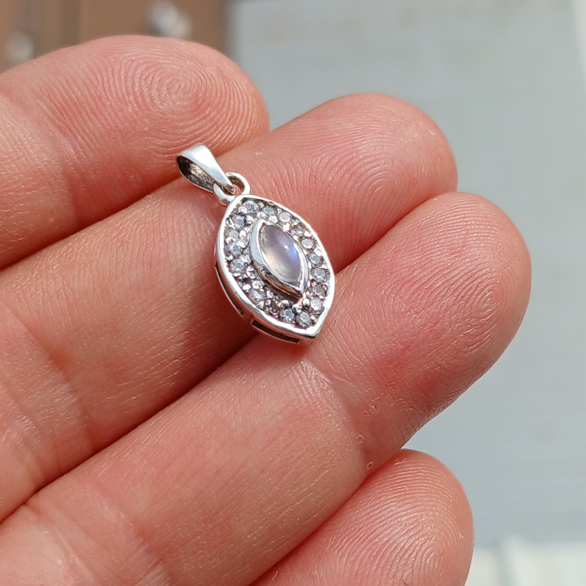 A stunning Moonstone Pendant in sterling silver, featuring a central moonstone surrounded by seven sparkling cubic zirconias.