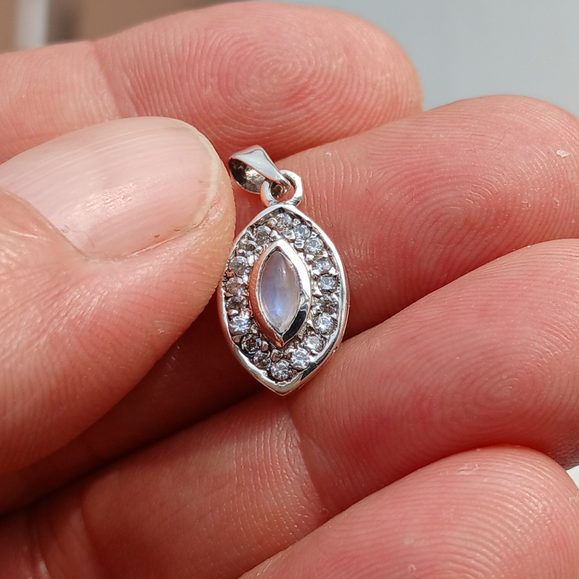 A stunning Moonstone Pendant in sterling silver, featuring a central moonstone surrounded by seven sparkling cubic zirconias.