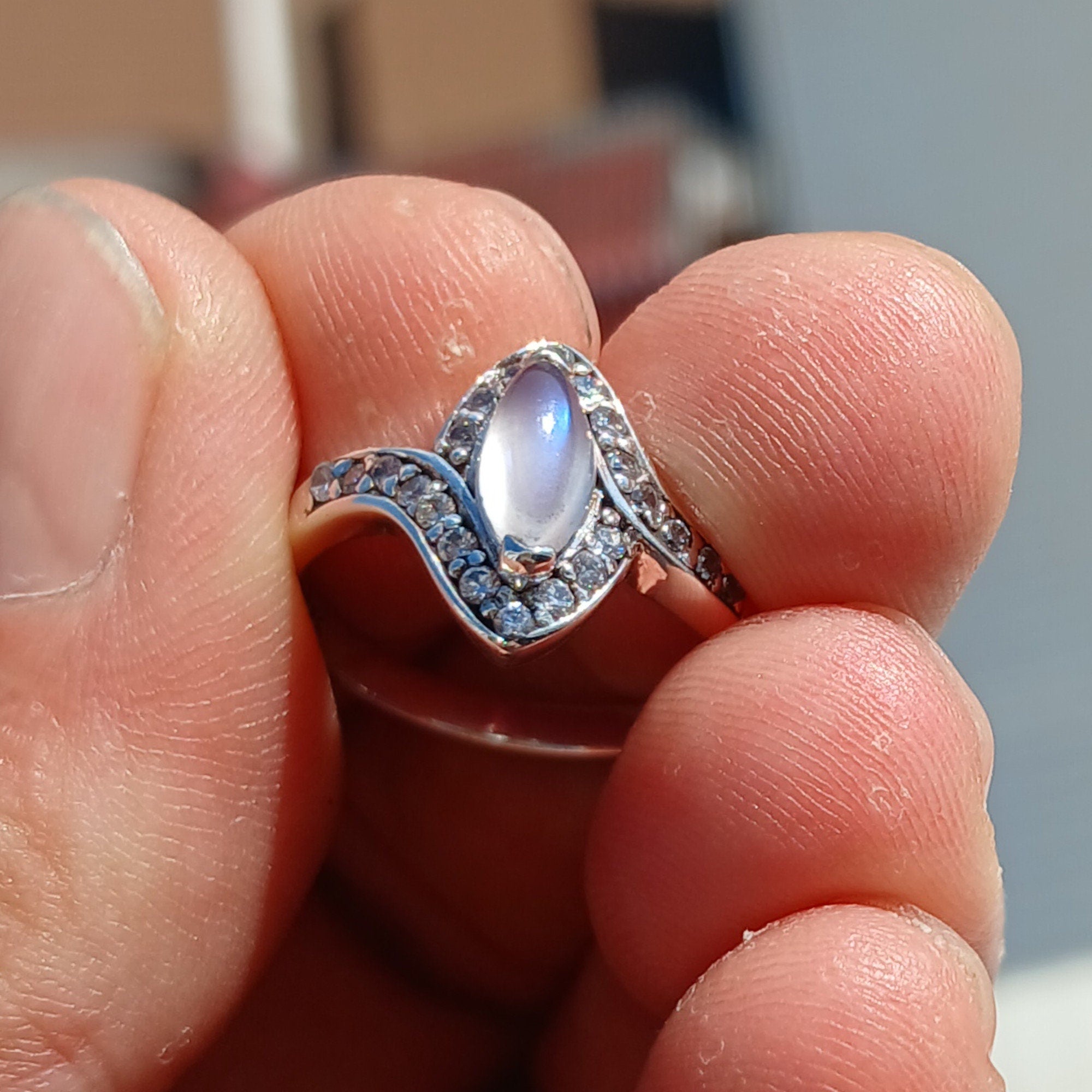 A stunning Moonstone Ring featuring a marquise-shaped Ceylon Moonstone surrounded by 22 cubic zirconia stones, set in a polished sterling silver band.