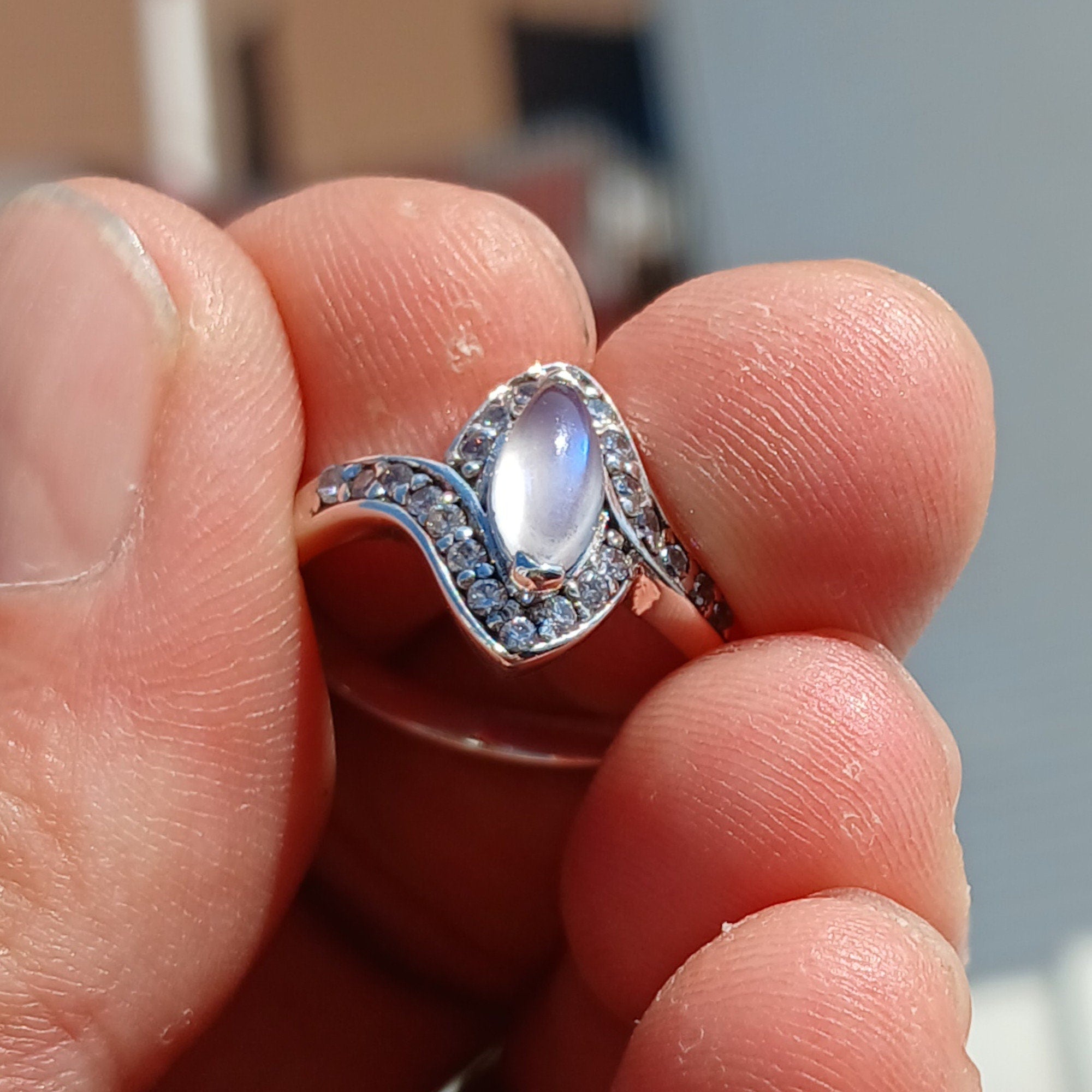 A stunning Moonstone Ring featuring a marquise-shaped Ceylon Moonstone surrounded by 22 cubic zirconia stones, set in a polished sterling silver band.