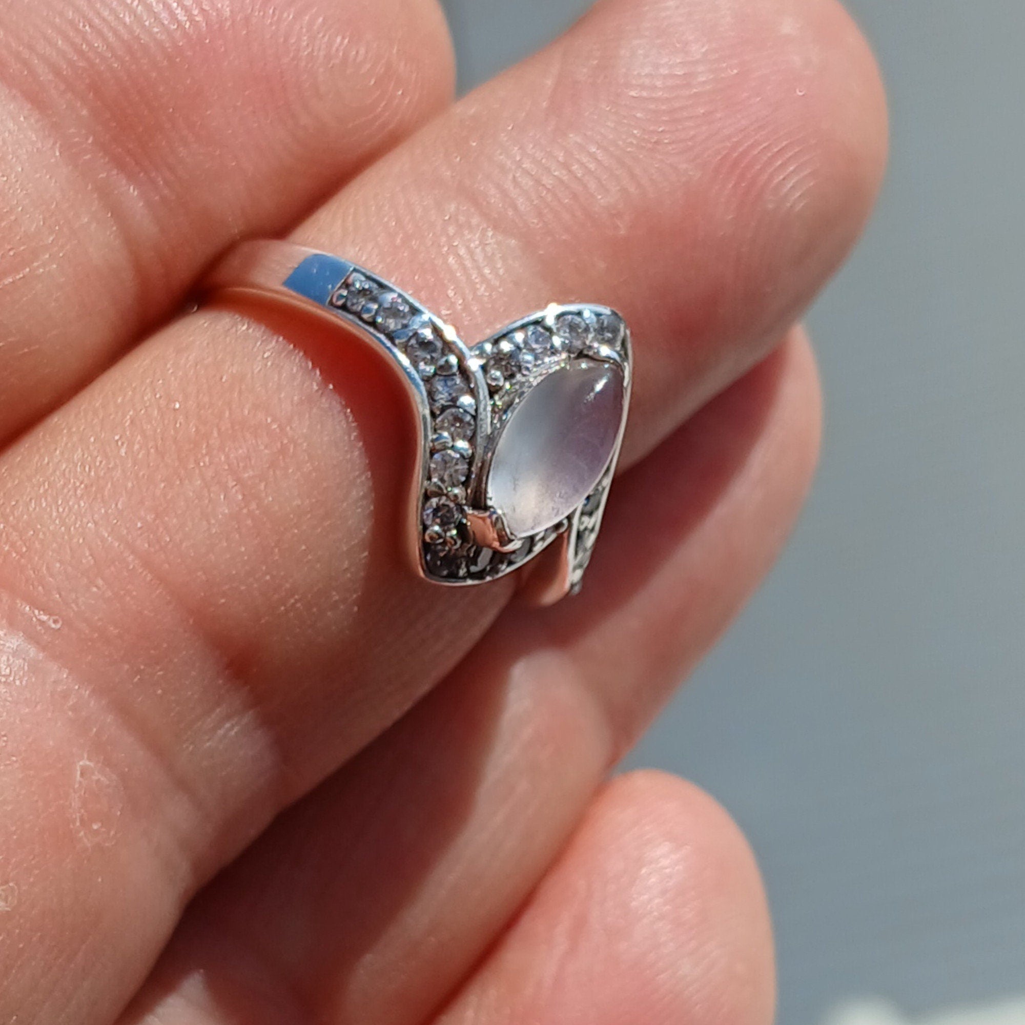 A stunning Moonstone Ring featuring a marquise-shaped Ceylon Moonstone surrounded by 22 cubic zirconia stones, set in a polished sterling silver band.