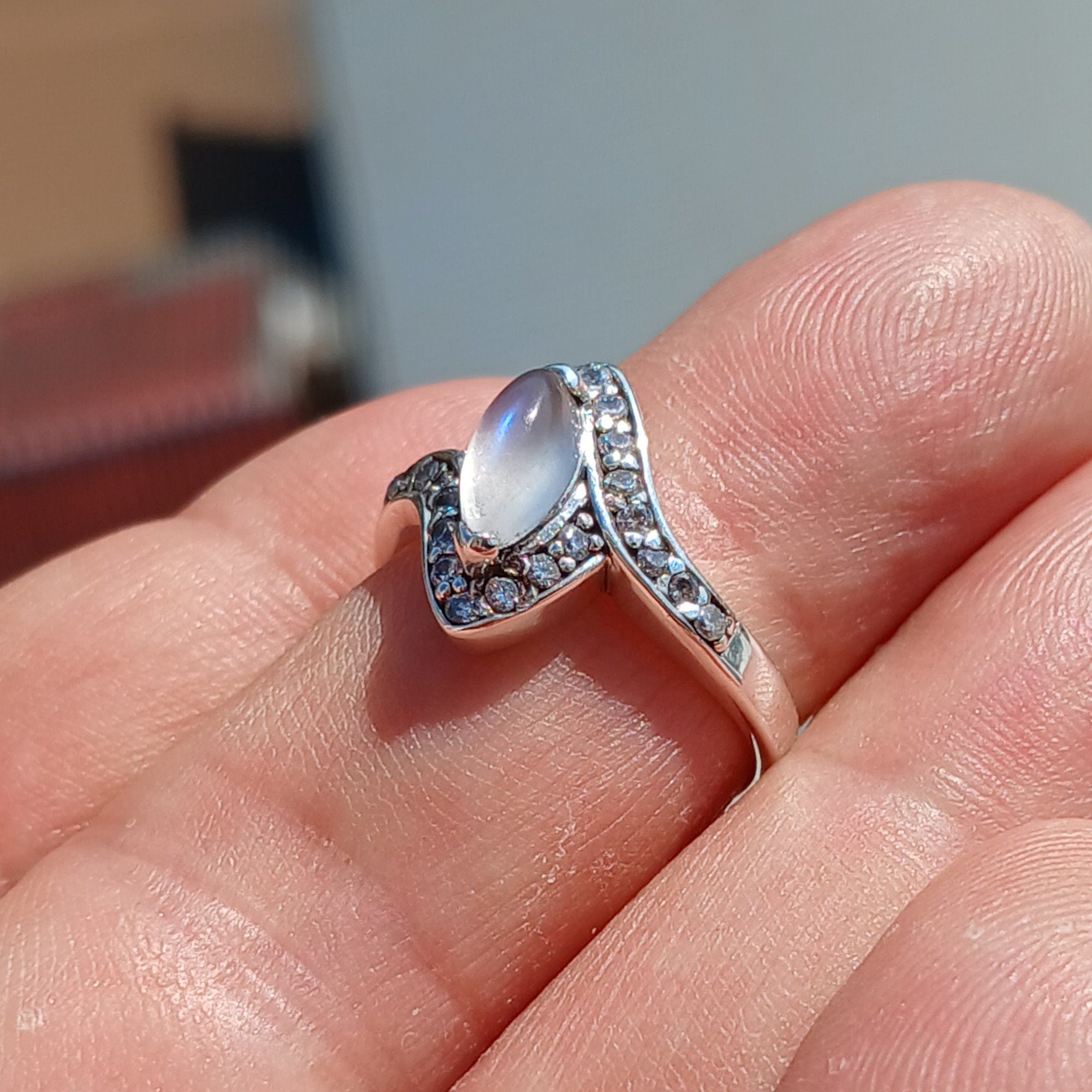 A stunning Moonstone Ring featuring a marquise-shaped Ceylon Moonstone surrounded by 22 cubic zirconia stones, set in a polished sterling silver band.