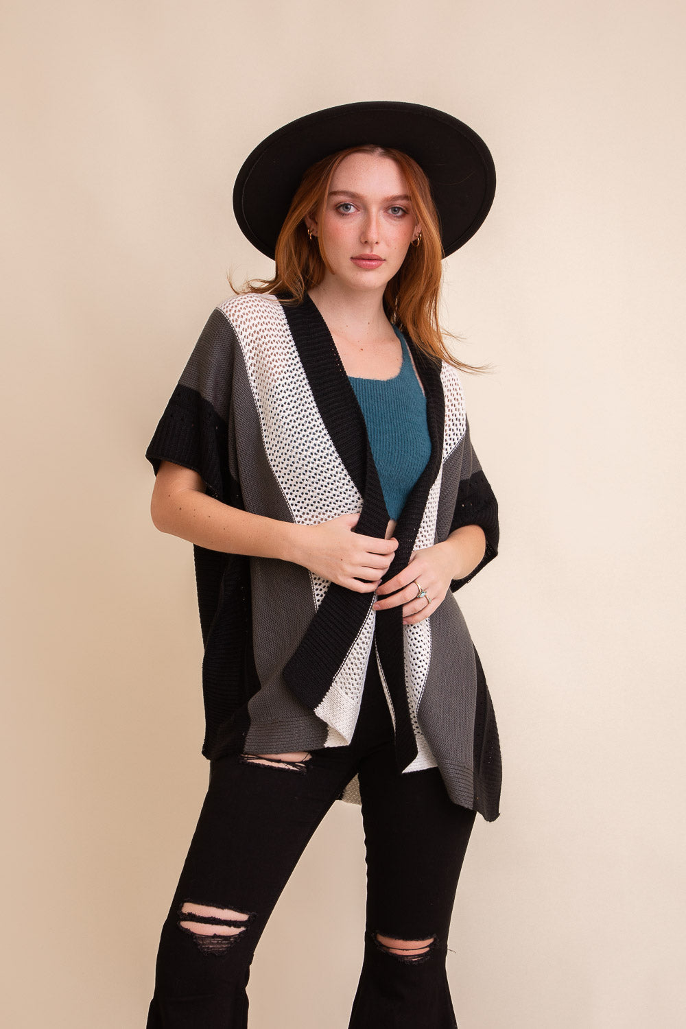 A vibrant multi-colored striped knit poncho draped elegantly, showcasing its cozy fabric and stylish design.