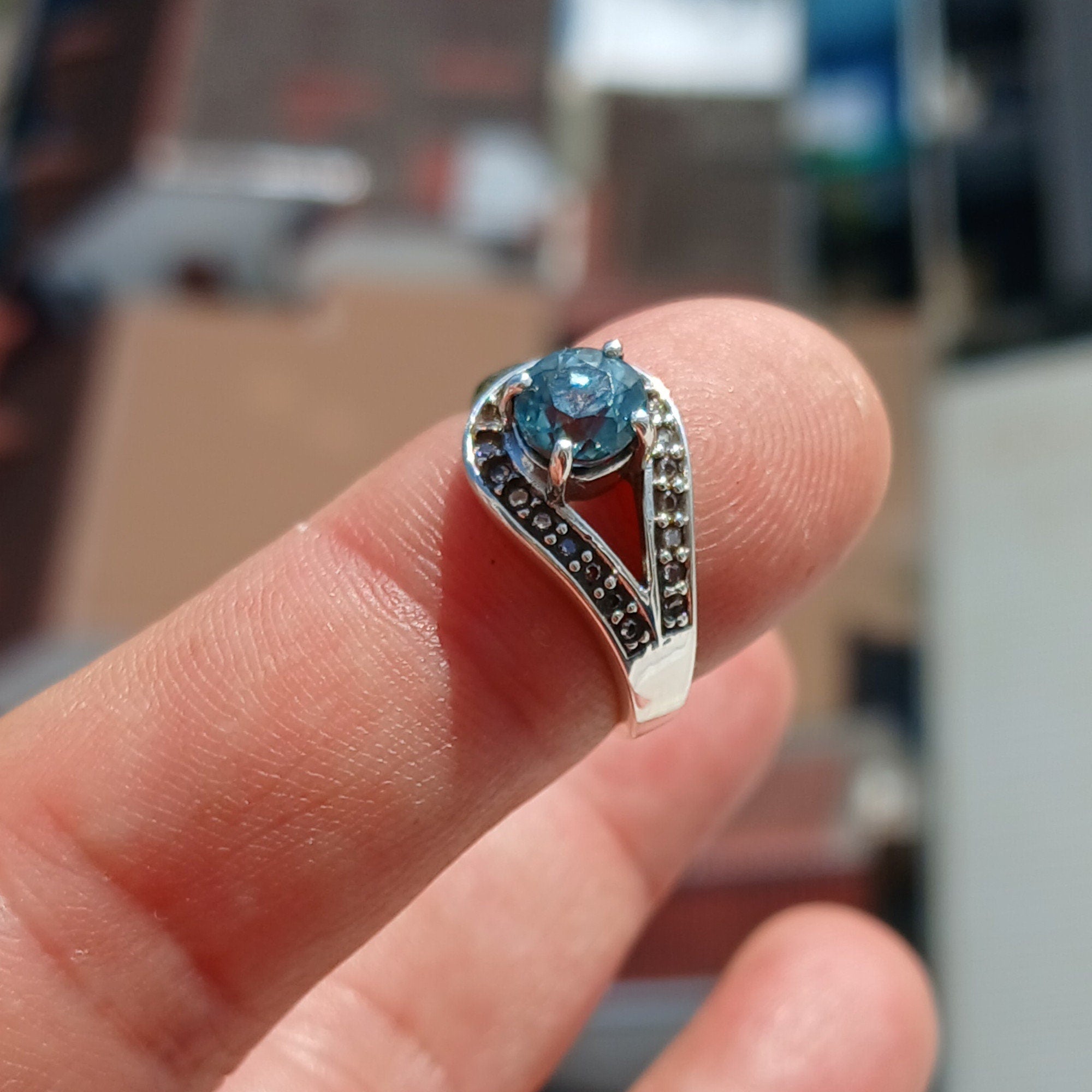 Natural Blue Zircon Ring in sterling silver with CZ accents, showcasing a round cut blue Zircon and elegant design.