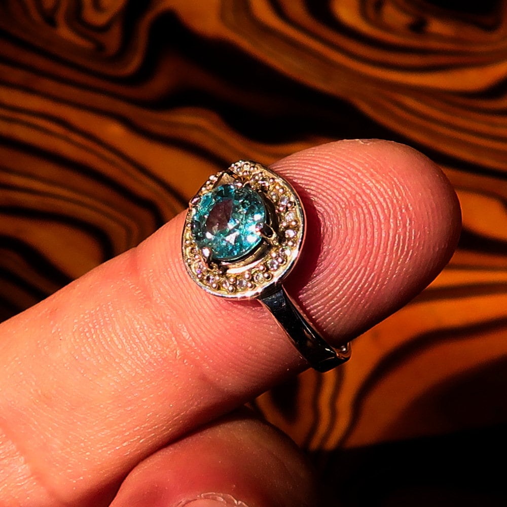 Natural Blue Zircon Ring featuring a round cut gemstone in polished Sterling Silver with 23 CZ accents.