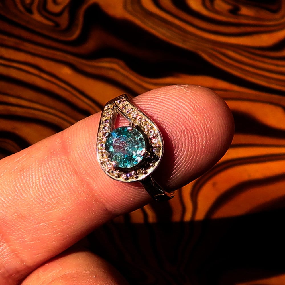 Natural Blue Zircon Ring featuring a round cut gemstone in polished Sterling Silver with 23 CZ accents.