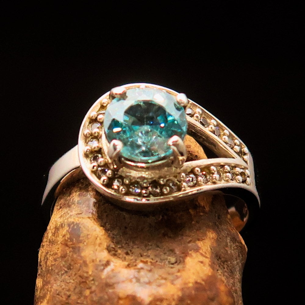 Natural Blue Zircon Ring featuring a round cut gemstone in polished Sterling Silver with 23 CZ accents.