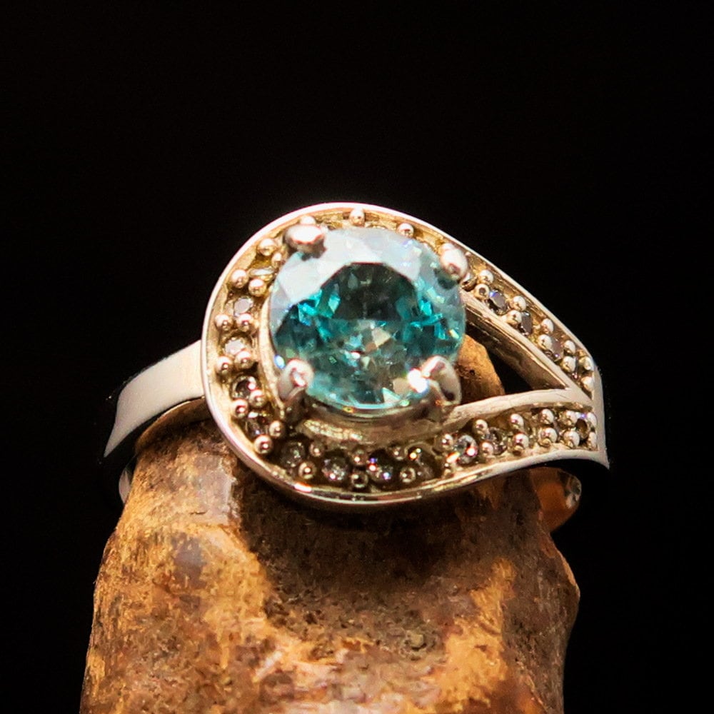 Natural Blue Zircon Ring featuring a round cut gemstone in polished Sterling Silver with 23 CZ accents.