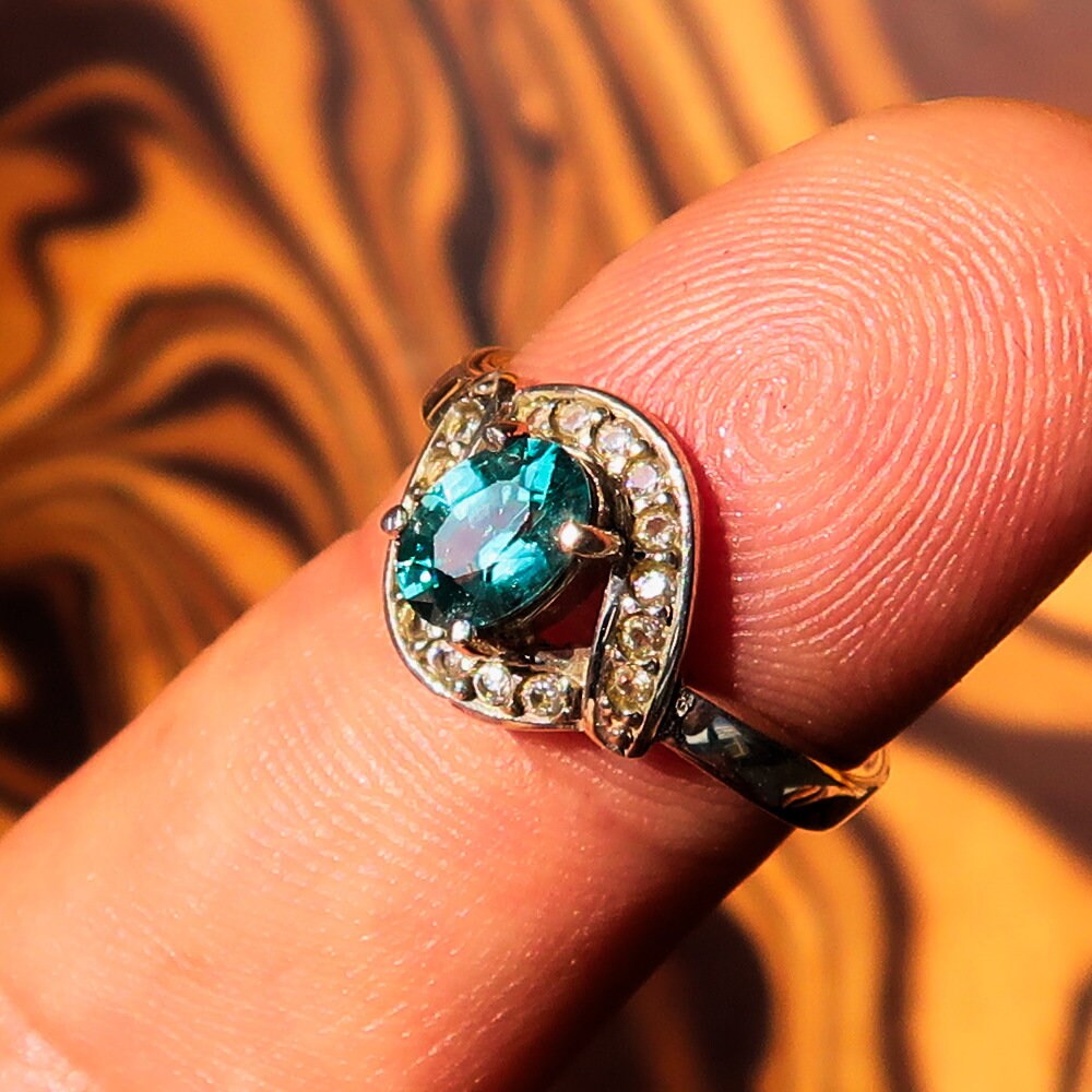 Handmade sterling silver ring featuring a natural oval cut blue Zircon centerpiece surrounded by sparkling CZ stones.