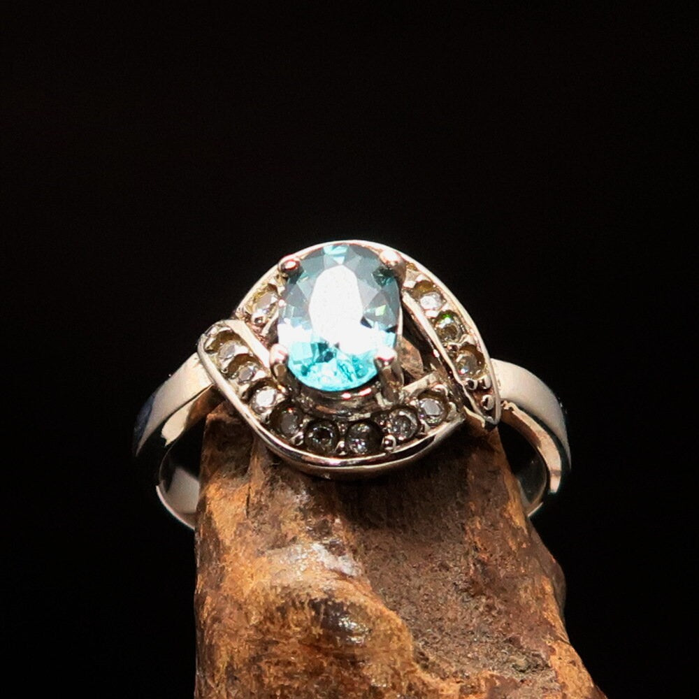 Handmade sterling silver ring featuring a natural oval cut blue Zircon centerpiece surrounded by sparkling CZ stones.