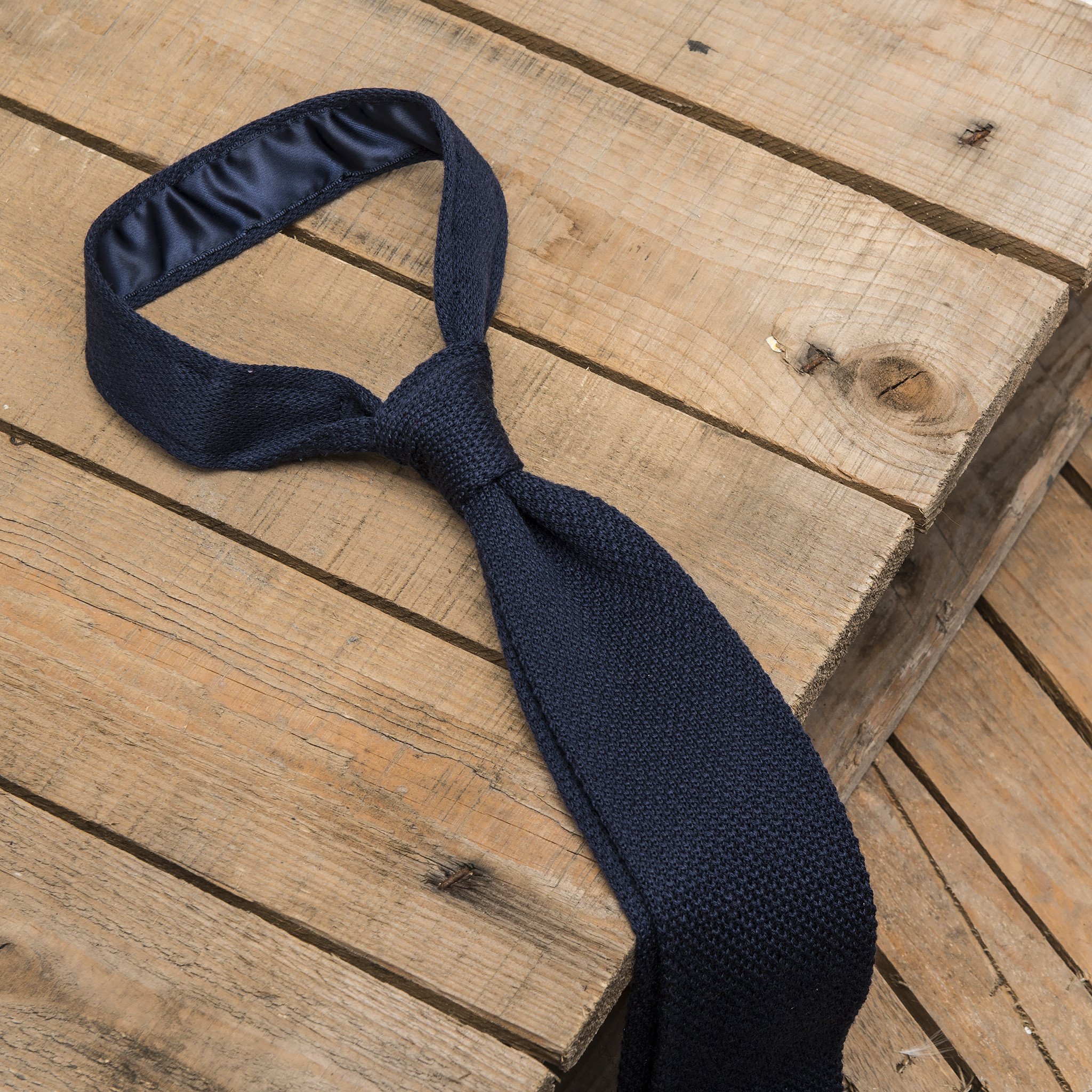 A luxurious navy blue knitted silk tie with a square end design, showcasing its rich color and texture.