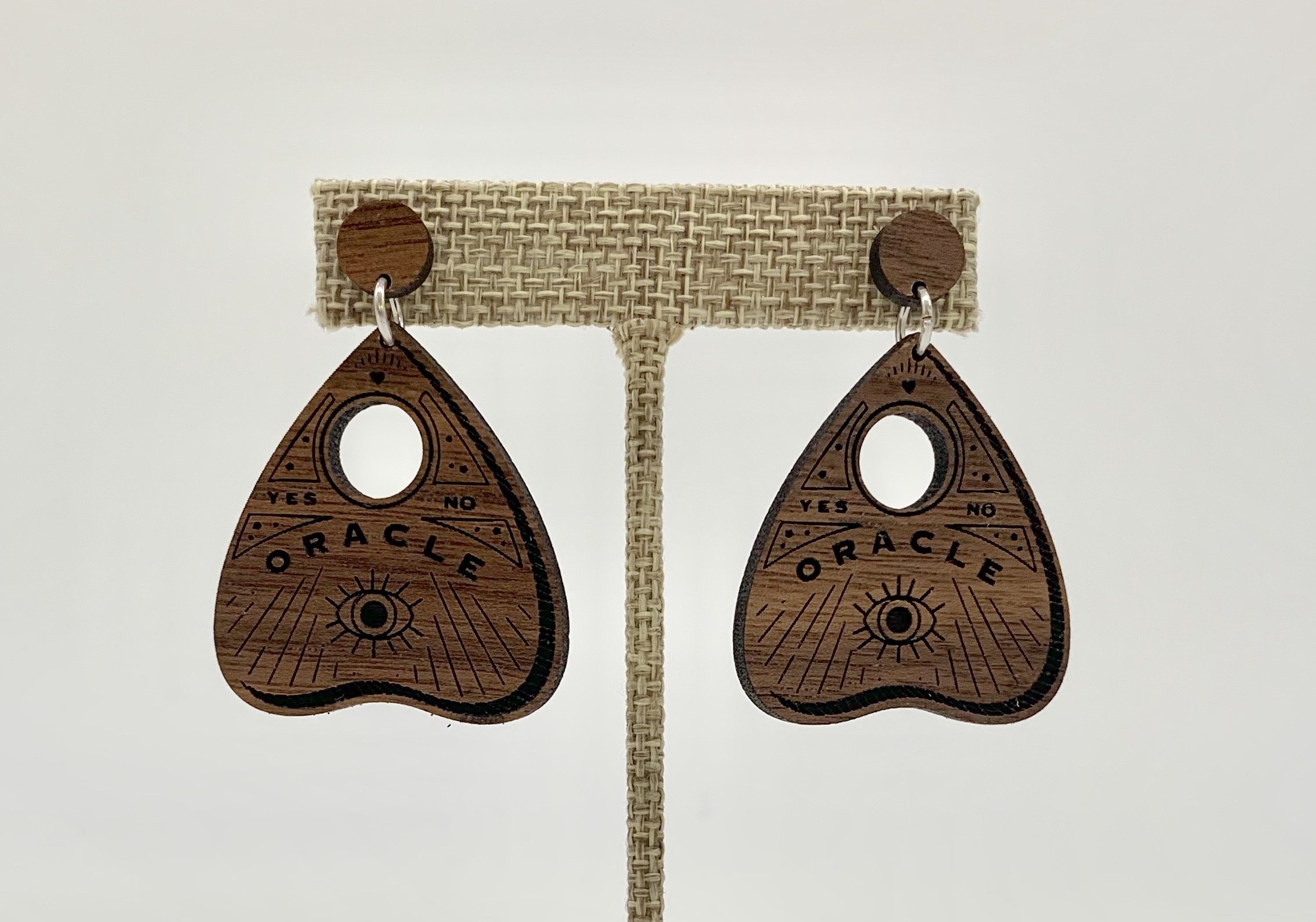 A pair of Ouija Earrings made from high-quality black walnut with stainless steel backings, showcasing a mystical design.