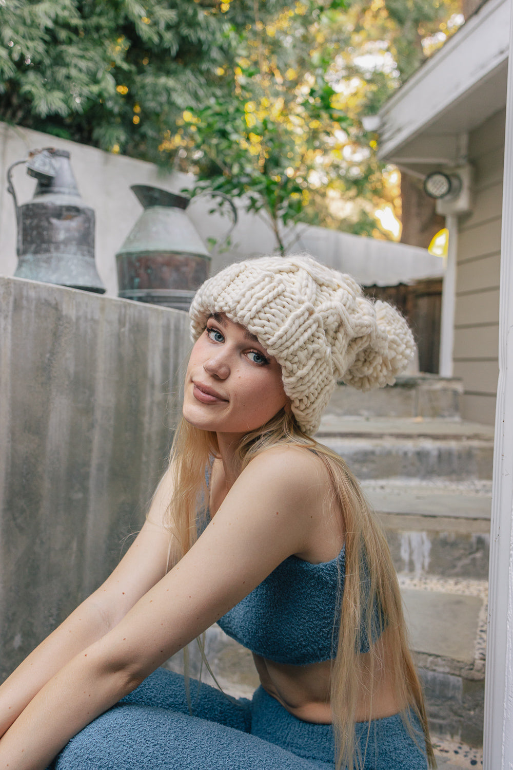 A stylish oversized chunky knit pom beanie in a cozy winter setting, featuring a playful pom on top and a chunky knit design.