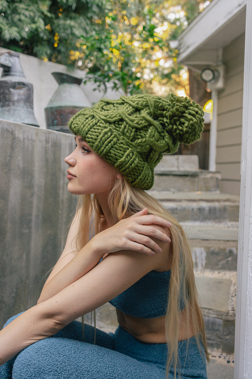 A stylish oversized chunky knit pom beanie in a cozy winter setting, featuring a playful pom on top and a chunky knit design.