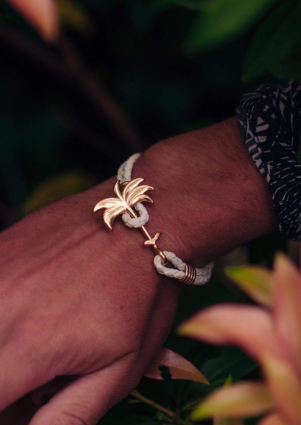 The Palm Band - Paradise Rose featuring a rose gold palm tree charm on a white braided leather bracelet, symbolizing positivity and happiness.