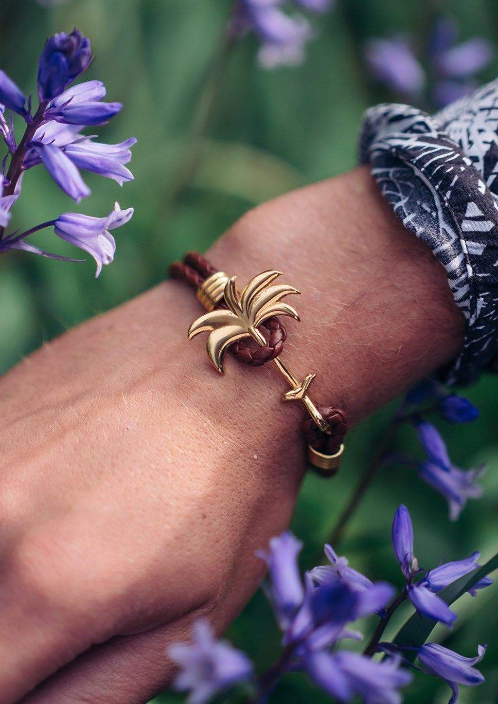 Palm Band - Sunrise Gold featuring a gold palm tree anchor on a thick braided brown leather bracelet, symbolizing positivity and happiness.