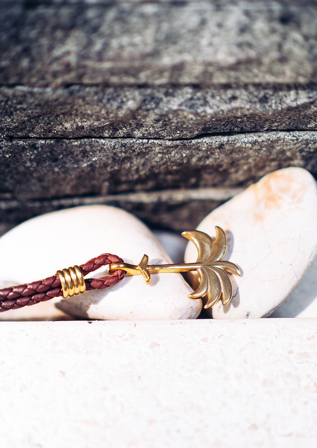 Palm Band - Sunrise Gold featuring a gold palm tree anchor on a thick braided brown leather bracelet, symbolizing positivity and happiness.