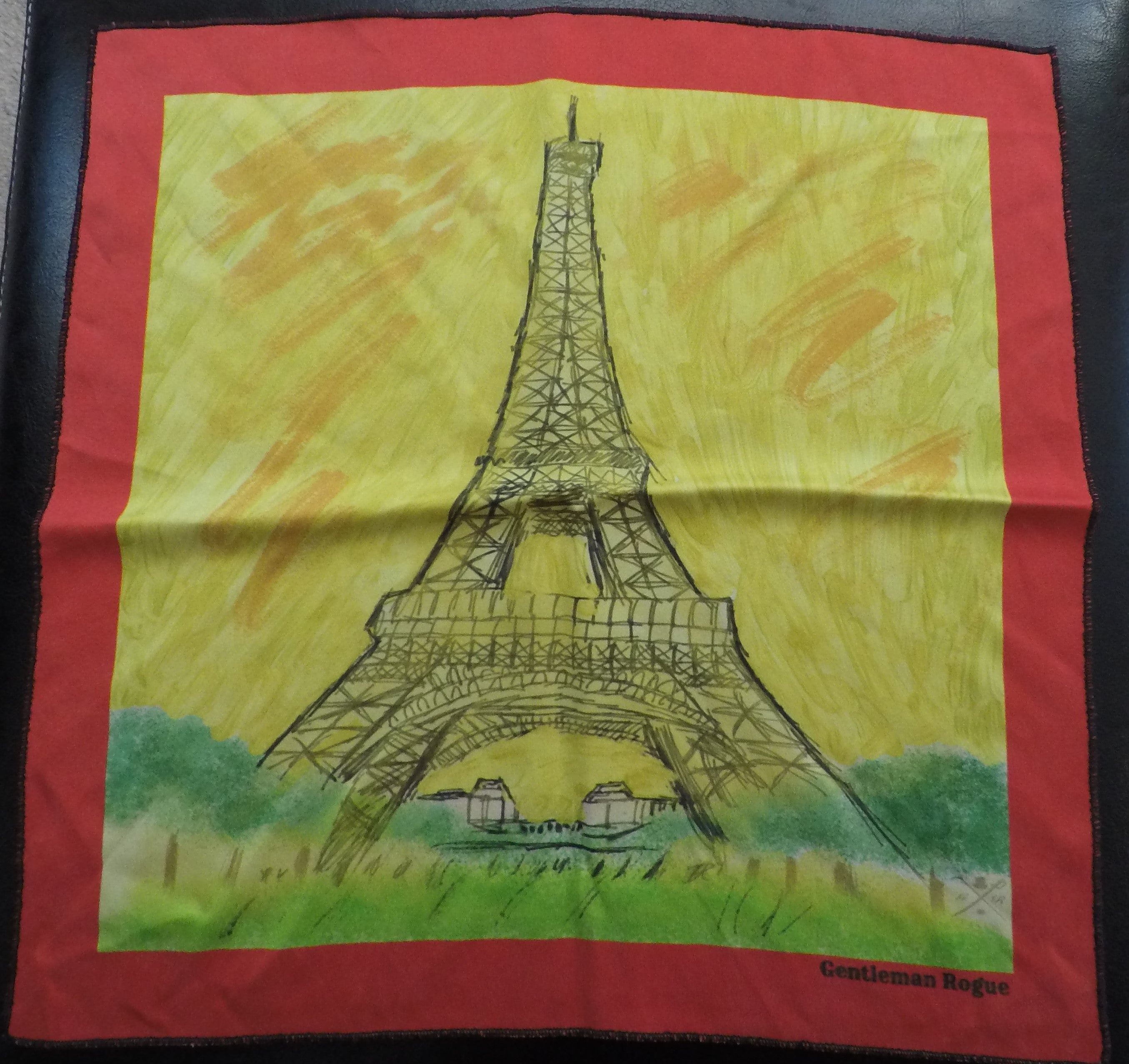 Elegant silk pocket square featuring a hand-sketched Eiffel Tower design with a vibrant yellow background and a red border.