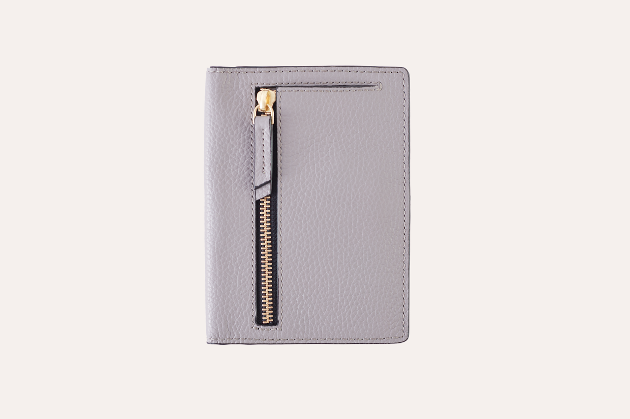 A stylish passport sleeve made of genuine pebble leather, featuring a button closure, card slots, and an external zipper pocket.