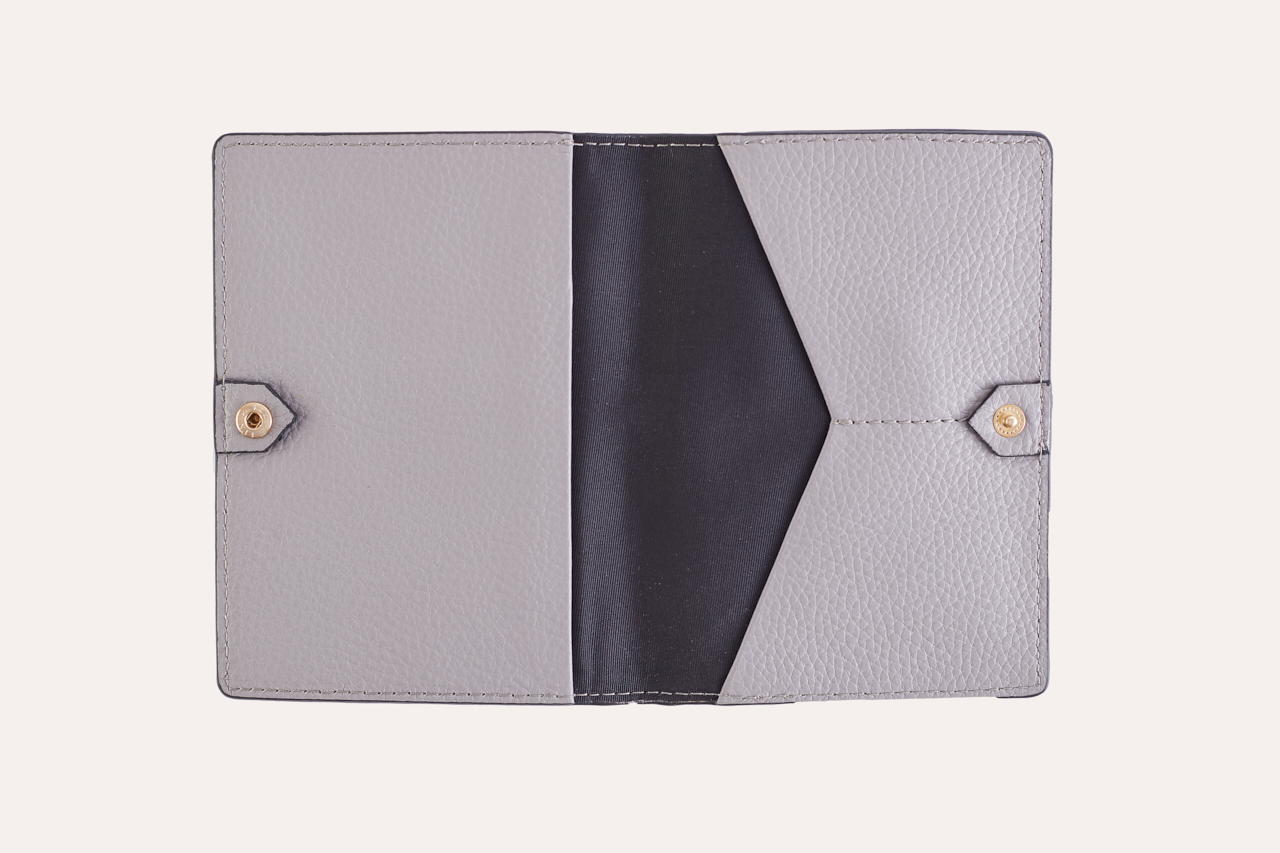 A stylish passport sleeve made of genuine pebble leather, featuring a button closure, card slots, and an external zipper pocket.