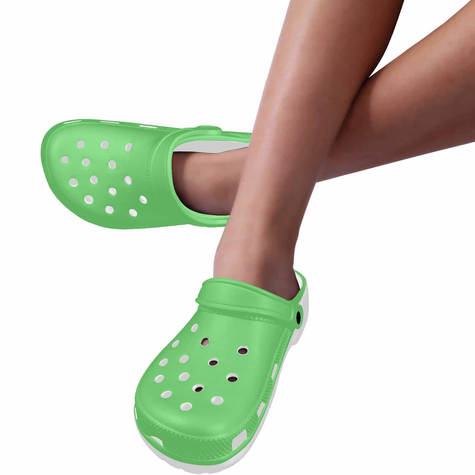 Pastel green adult clogs made from lightweight EVA material, featuring ventilation ports and pivoting heel straps for a secure fit.