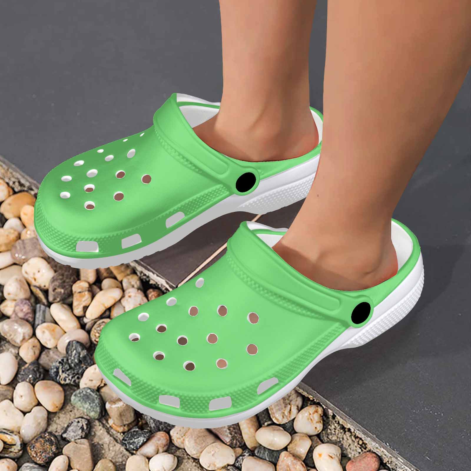 Pastel green adult clogs made from lightweight EVA material, featuring ventilation ports and pivoting heel straps for a secure fit.