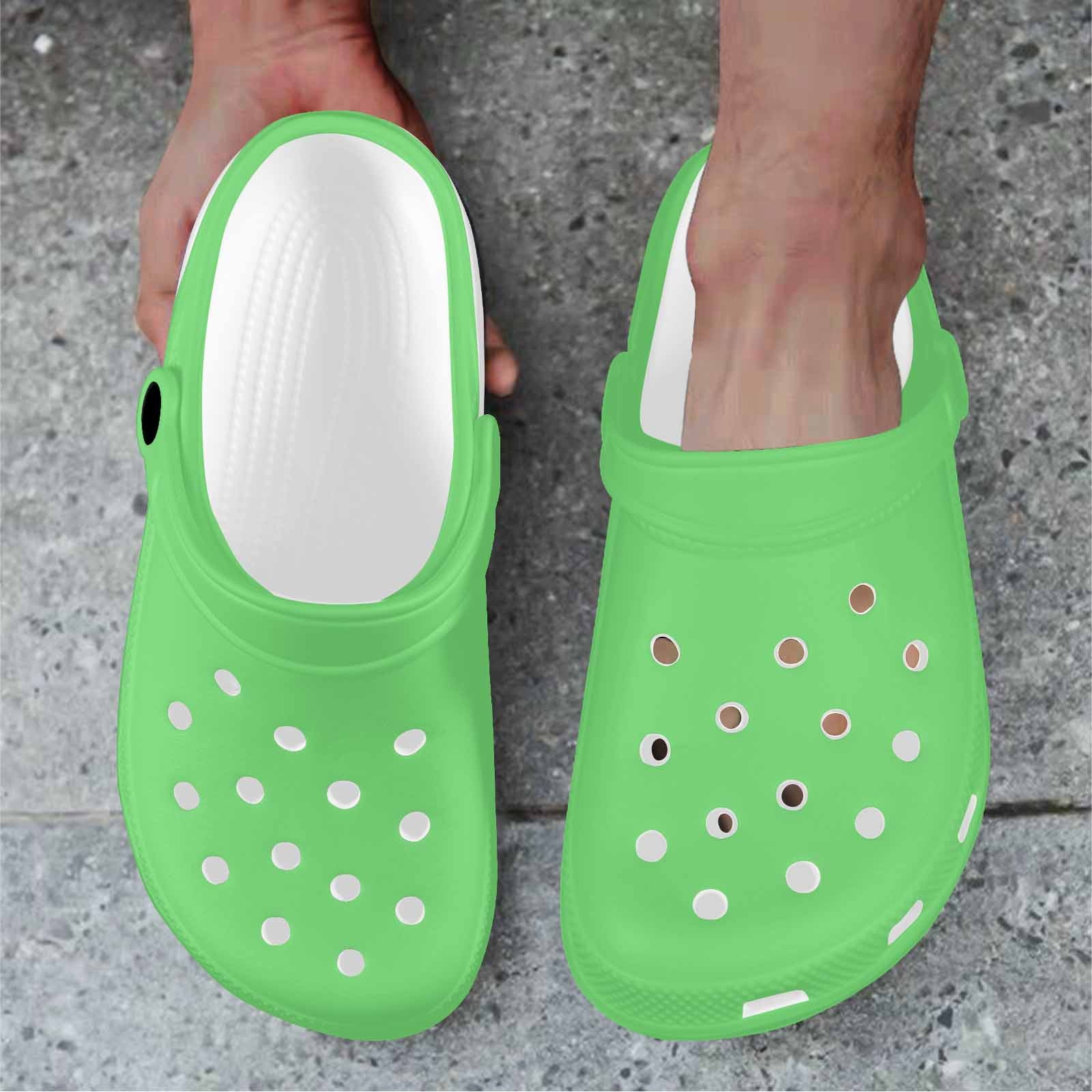 Pastel green adult clogs made from lightweight EVA material, featuring ventilation ports and pivoting heel straps for a secure fit.