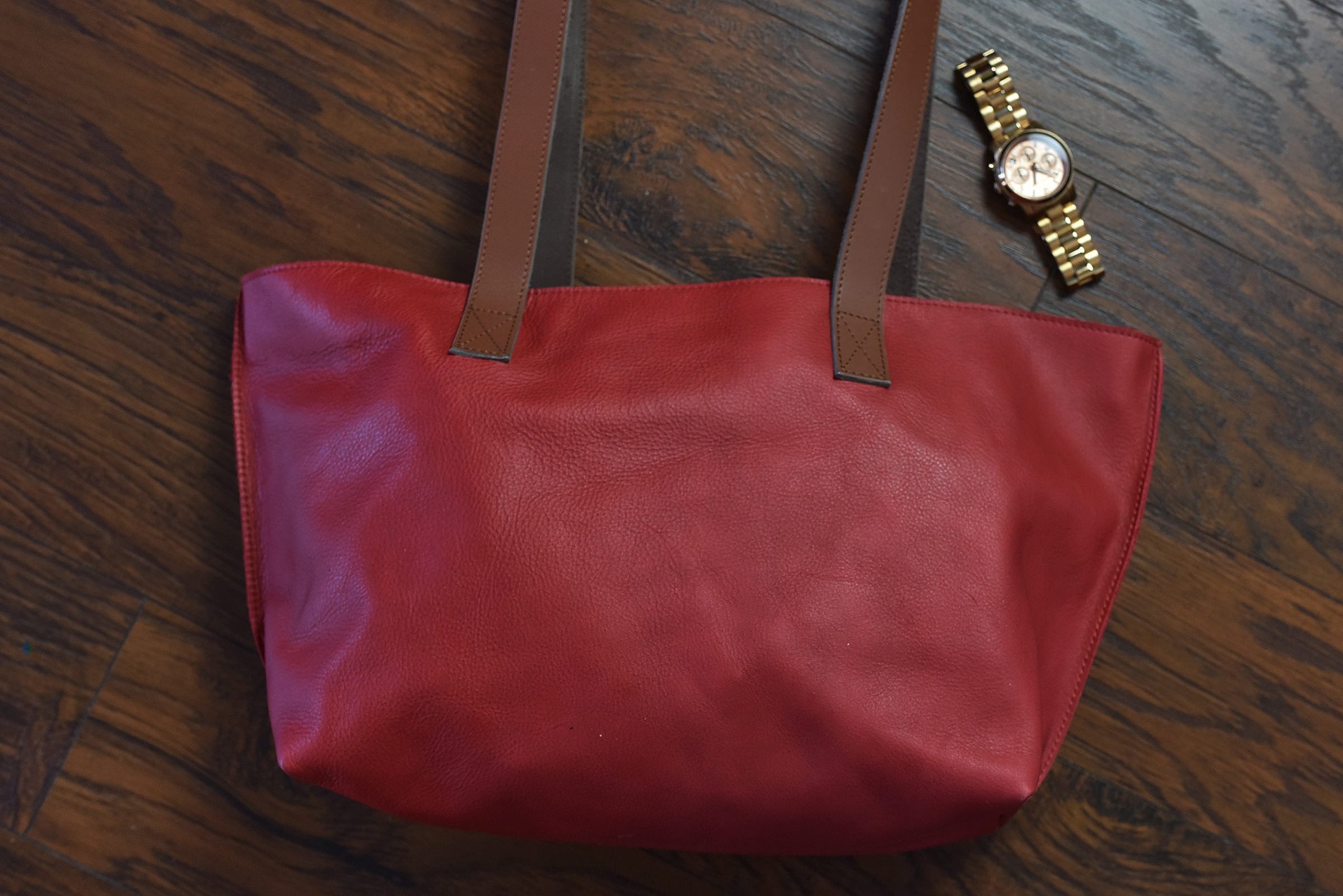 A stylish red tote bag made of genuine leather with a bowl-shaped design and comfortable shoulder handles.