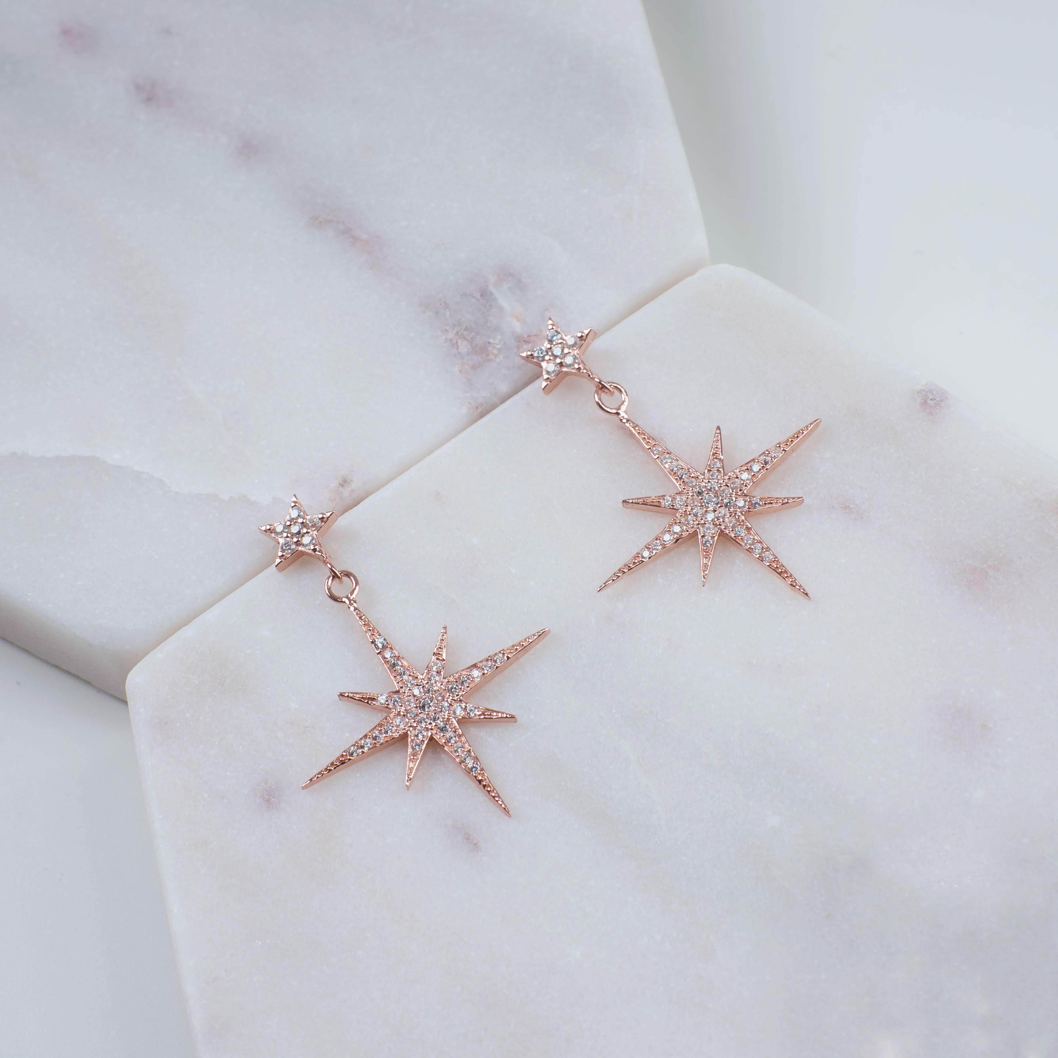 Petite Star Burst Drop Earrings in Rosegold featuring a larger starburst and smaller stud, adorned with cubic zirconia for added sparkle.