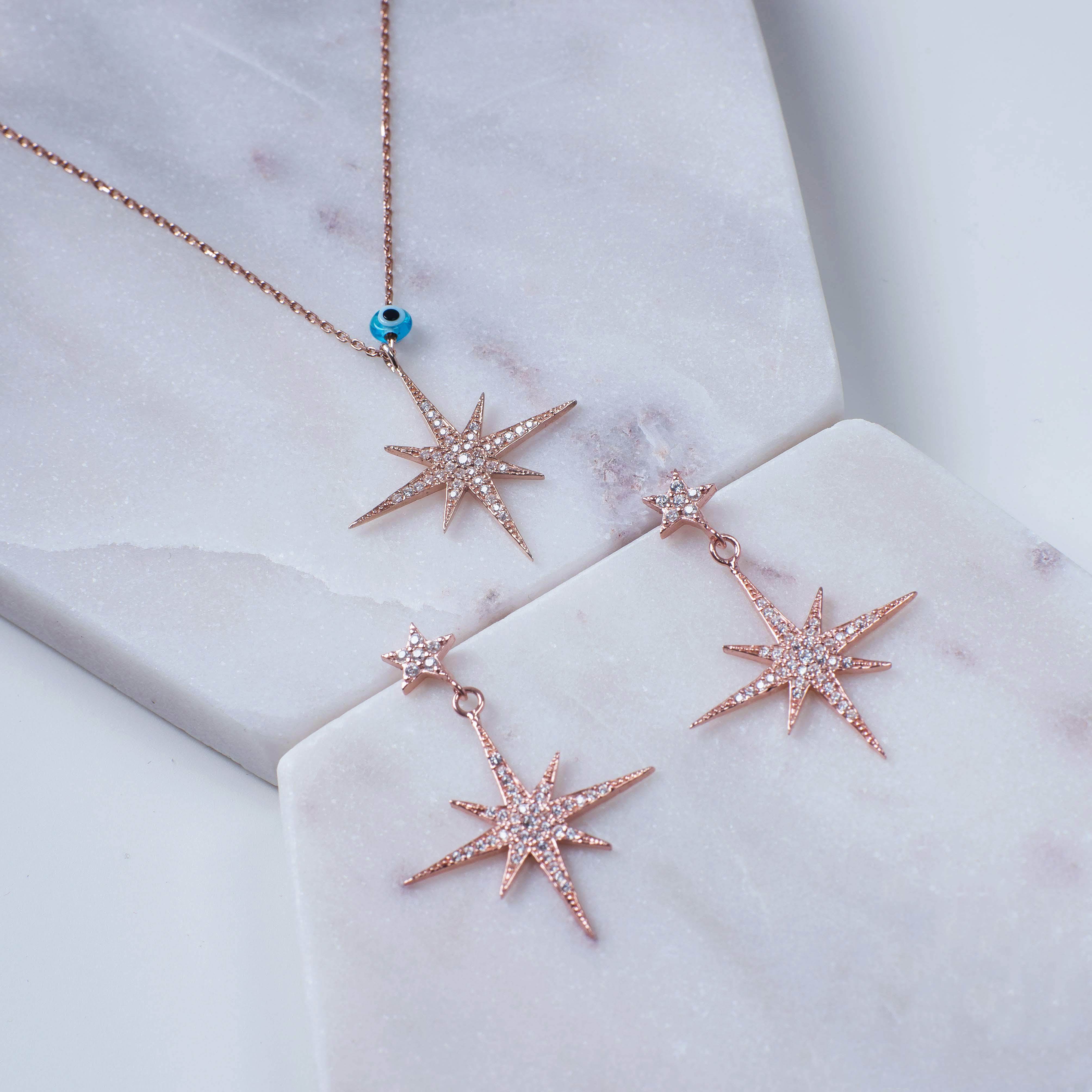 Petite Star Burst Drop Earrings in Rosegold featuring a larger starburst and smaller stud, adorned with cubic zirconia for added sparkle.