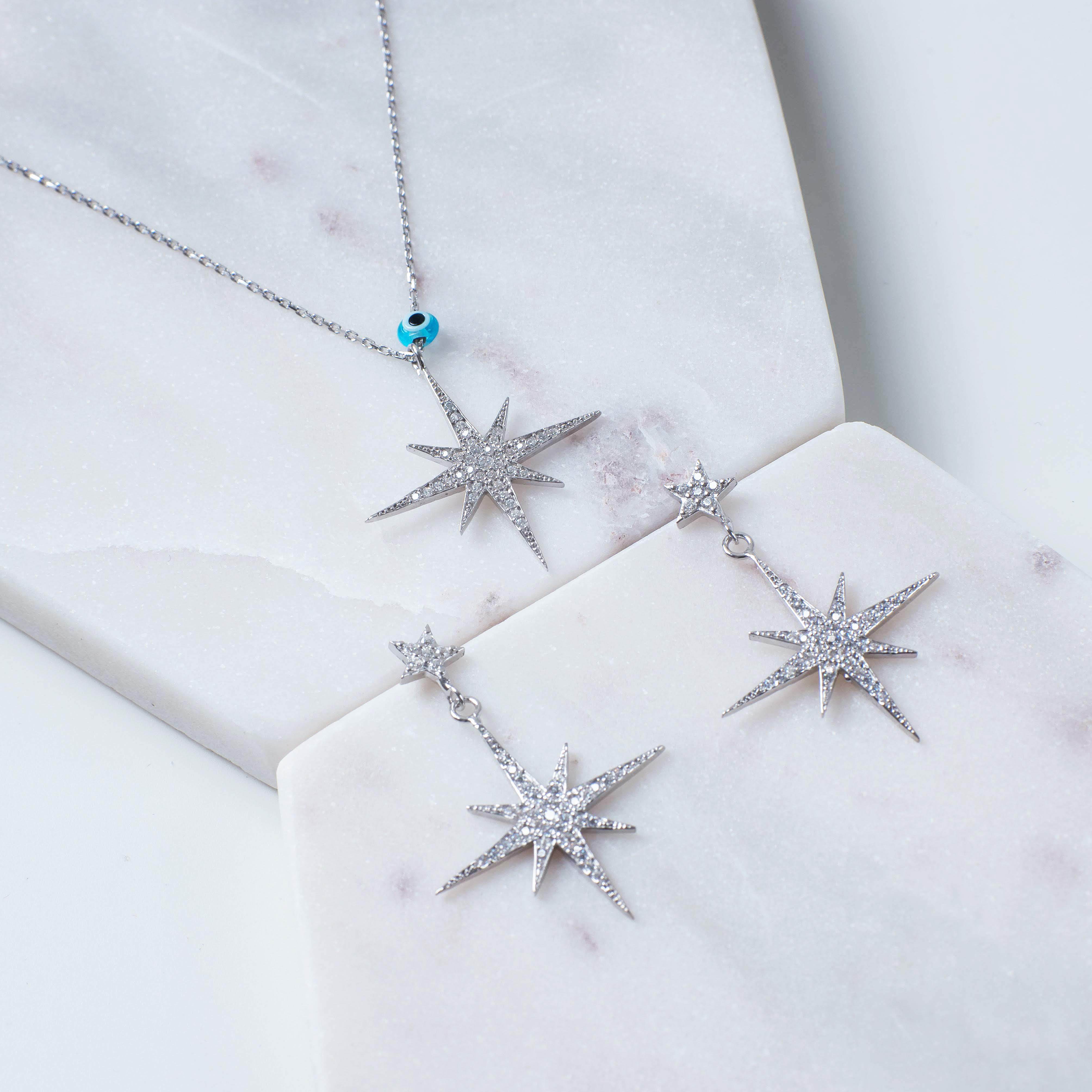 Petite Star Burst Drop Earrings in Silver featuring sparkling cubic zirconia and a unique starburst design.