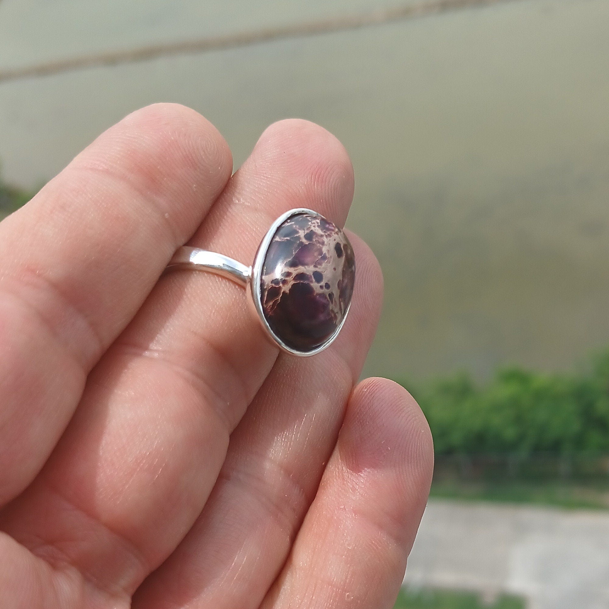 A beautiful sterling silver ring featuring a vibrant oval-shaped purple Pietersite gemstone, showcasing its unique design and craftsmanship.