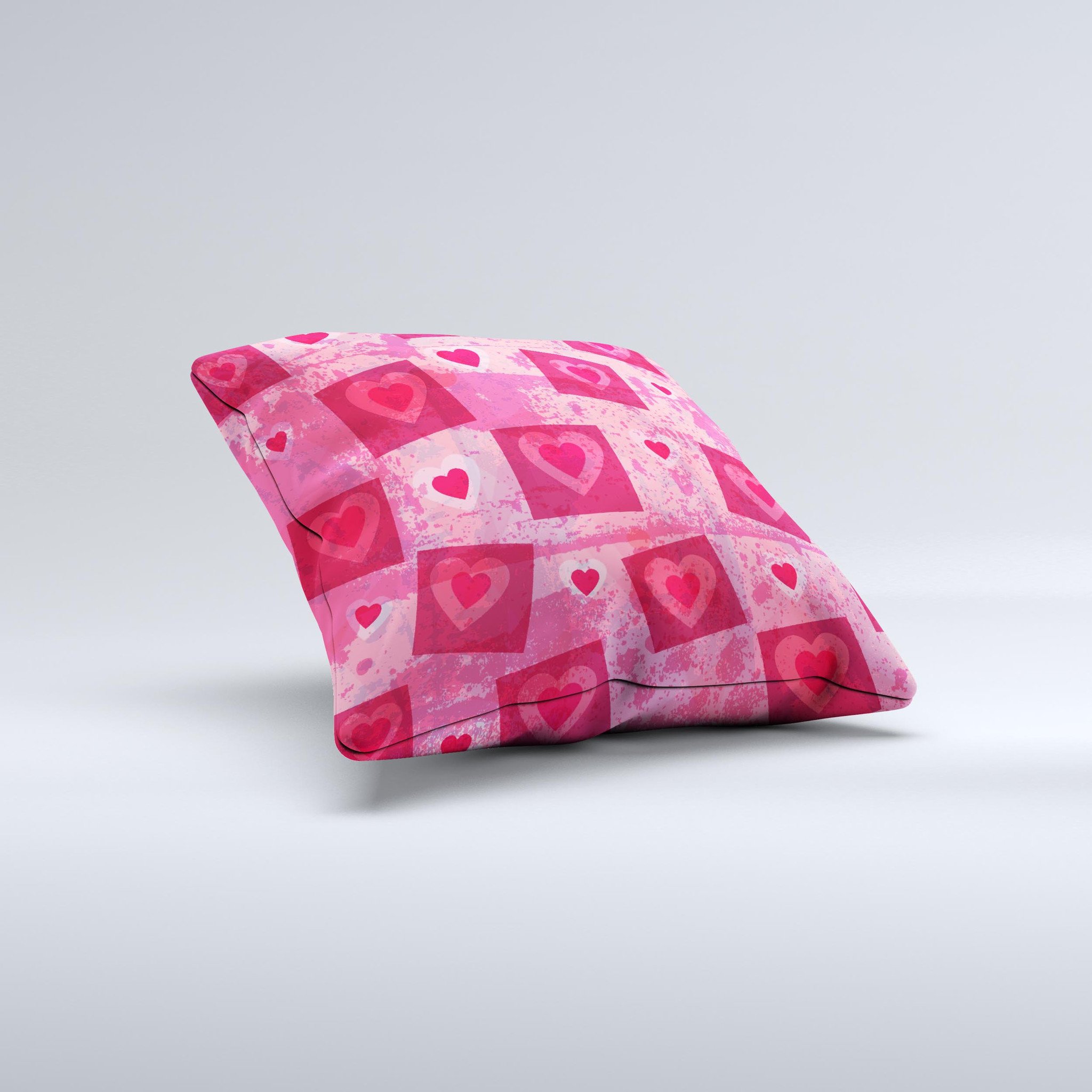 A decorative throw pillow featuring a unique design of pink and red hearts arranged in blocks, handcrafted in Virginia.