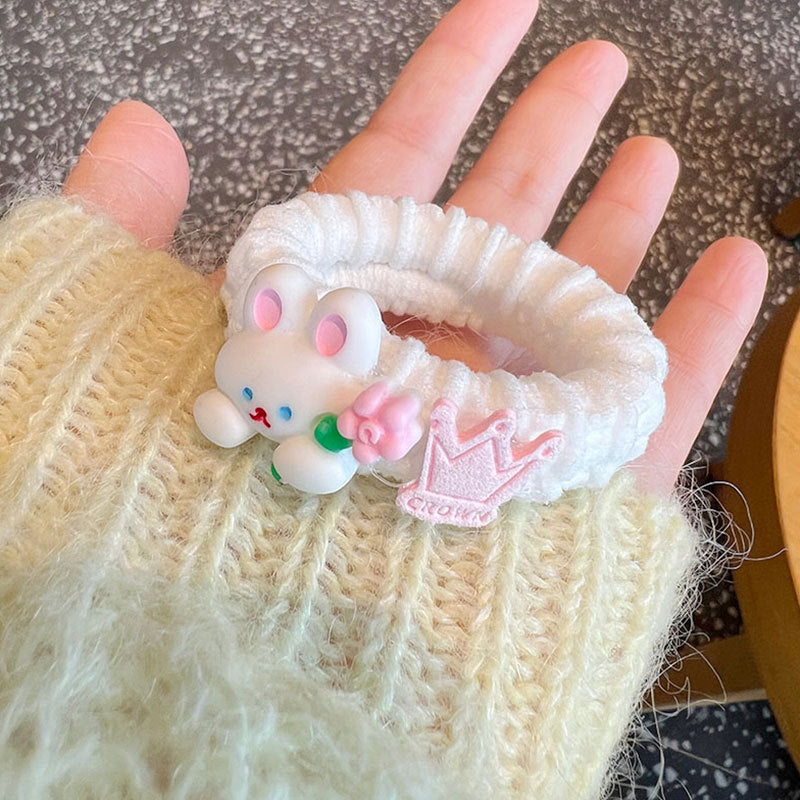 A collection of four pink scrunchies featuring cute animal designs, held by a person, showcasing their stylish and gentle nature.