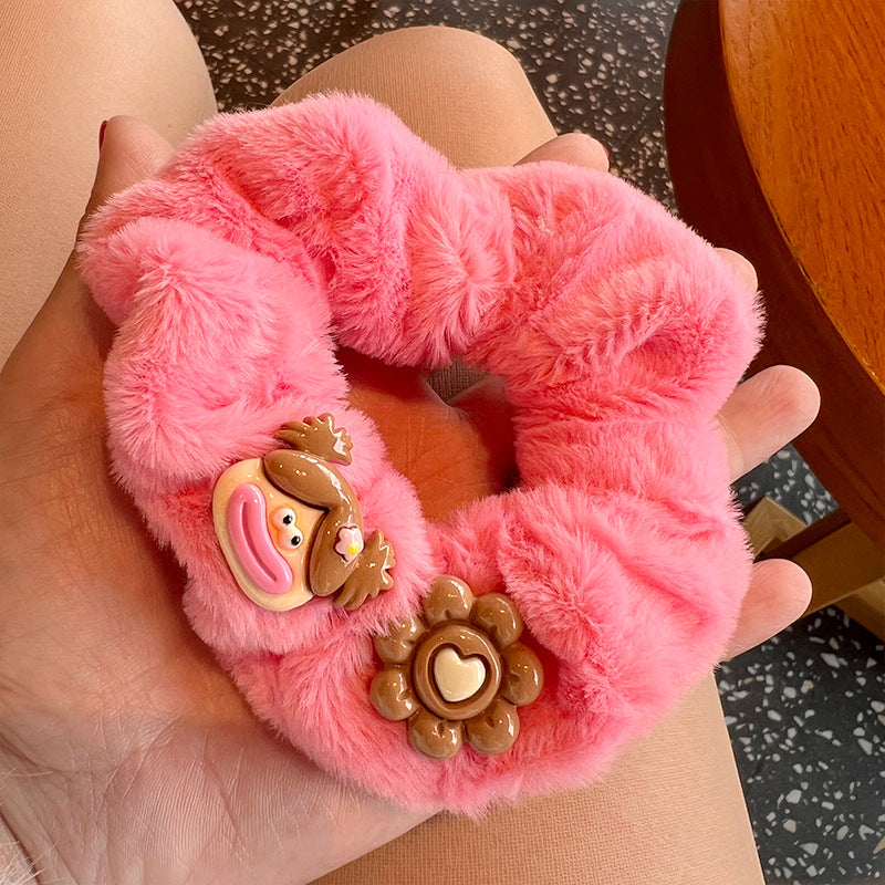 A cute pink and brown plush clown hair tie featuring fuzzy gloves, perfect for adding a playful touch to hairstyles.