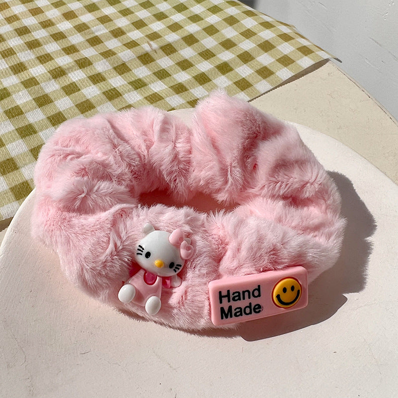 A vibrant pink hair tie featuring fuzzy textures, held by a woman's hand, showcasing a playful and unique design.