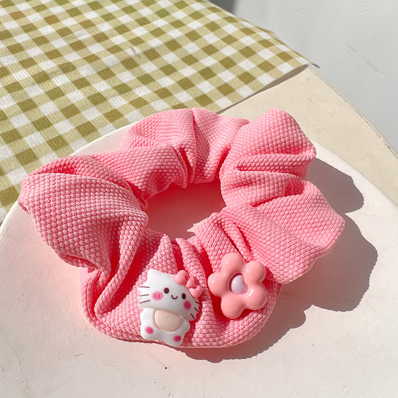 A vibrant pink hair tie featuring fuzzy textures, held by a woman's hand, showcasing a playful and unique design.