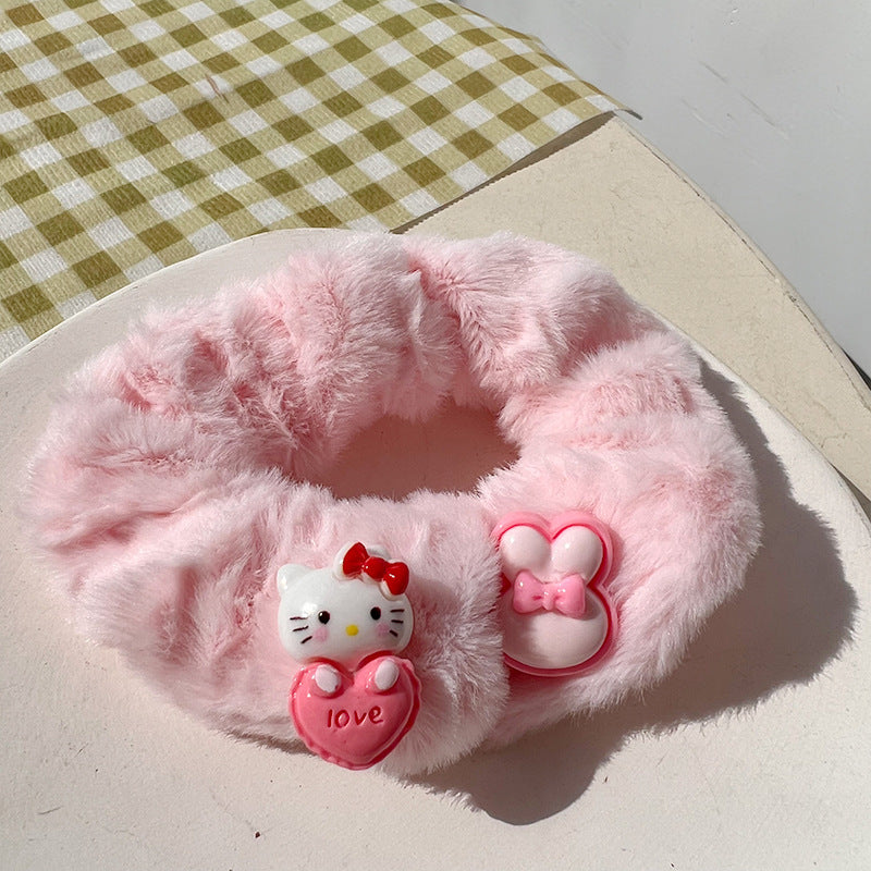 A vibrant pink hair tie featuring fuzzy textures, held by a woman's hand, showcasing a playful and unique design.