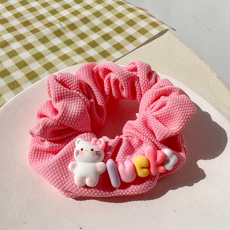 A vibrant pink hair tie featuring fuzzy textures, held by a woman's hand, showcasing a playful and unique design.