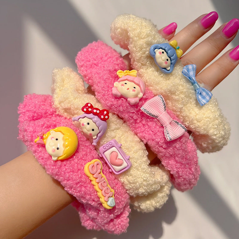 A pair of pink curly plush hair ties featuring cartoon characters, perfect for adding charm to hairstyles.