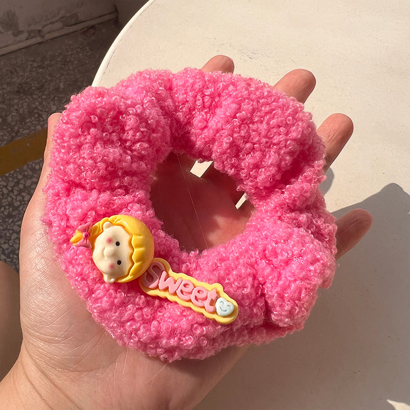 A pair of pink curly plush hair ties featuring cartoon characters, perfect for adding charm to hairstyles.